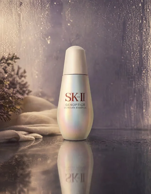 Cosmetic bottle standing on a reflective wet surface against a purple background